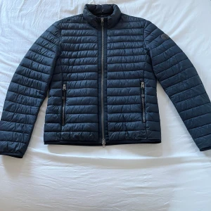 Marc O’Polo jacka - Säljer en stilren mörkblå jacka från Marc O’Polo Jackan har en dragkedja framtill och två praktiska fickor med dragkedjor. Perfekt för våren. Jacka är i storlek M och passar mig perfekt som är 185. Jacka ger en bra helhet intryck men finnas några mindre defekter. Nypris cirka 1500-2000 kr