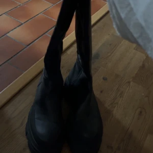 Svarta boots med dragkedja - Säljer ett par svarta boots med dragkedja. De har en robust sula och är perfekta för höst och vinter. Stilrena och enkla att matcha med olika outfits. Har aldrig använt dom. Står bara hemma bättre att sälja😊