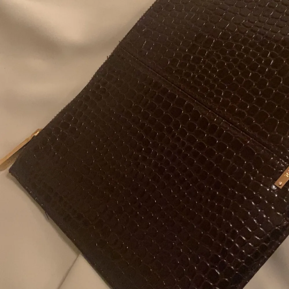 Elegant brun/röd datorväska med krokodilmönster och gulddetaljer. Väskan har en dragkedja som ger en stilren look. Perfekt för att ge en touch av lyx till din outfit.. Laukut & Käsilaukut.