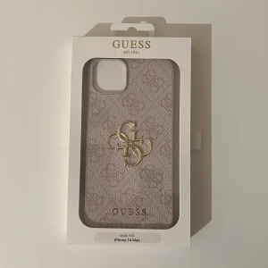 Guess mobilskal för iPhone 14 Max rosa/beige - Snyggt mobilskal från Guess för iPhone 14 Max. Skalet har en elegant beige färg med ett subtilt mönster och Guess-logotypen i guld. Det är designat för att ge bra skydd och har en slim profil för enkel användning. Förpackningen är oöppnad pågrund av felköp och därmed aldrig använt. 