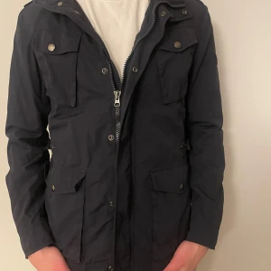 Mörkblå jacka från Woolrich - Säljer en riktigt snygg mörkblå jacka från Woolrich. Jackan är i fint skick. Säljer på grund av att den har blivit för liten tyvärr. Perfekt för höst/vår. Hör av er vid funderingar! 