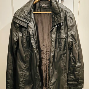 Svart jacka från KappAhl i storlek 48/50 - Säljer en svart jacka från KappAhl i storlek 48/50. Den har en stilren design med dragkedja och knappar framtill. Perfekt för höst och vår med sina långa ärmar och praktiska fickor. Jackan är i bra skick och redo för nya äventyr!