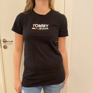 Svart t-shirt med tryck - Säljer en svart t-sjukt med tryck i uppstattad storlek S. Den har en klassisk passform med korta ärmar och ett tryck med märkesloggan i vitt och rött på bröstet. Perfekt för vardagsbruk eller en avslappnad stil. Skön och enkel att matcha med jeans eller shorts!