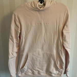 Ljusrosa hoodie från WeSC - Säljer en superfin ljusrosa hoodie från WeSC i storlek XS. Den har en känguruficka framtill och en diskret broderad text på bröstet. Perfekt för mysiga dagar eller en avslappnad stil. Huvan är mjuk och skön, och materialet känns riktigt bekvämt. Passar perfekt till jeans eller leggings!