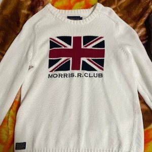 Morris Jack Stickad Flagga Rundhalsad  - Uppgradera din stil med denna unika rundhalsade tröja från Morris Jack! Den stickade designen med flaggmotiv ger en sportig och modern look. Perfekt för både vardag och fest. Bekväm passform och hög kvalitet. Säkra din i dag!