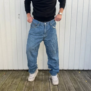 Levi's 550 Baggy Jeans - Säljer ett par klassiska Levi's 550 jeans i baggy stil. De är ljusblå och har en avslappnad passform med fem fickor och dragkedja. Perfekta för en casual look! 🕶️