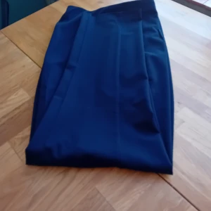 Bekväma Mörkblå byxor  dam från Ellos. - Säljer en elegant mörkblå byxor i ett stilrent och klassiskt snitt. Perfekt för både vardag och festliga tillfällen. byxor har en slät yta och är gjord i ett mjukt material som faller fint. Passar utmärkt till höst- och vintergarderoben.