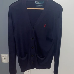 Mörkblå kofta från Polo Ralph Lauren - Säljer en snygg mörkblå kofta från Polo Ralph Lauren i storlek S men passar även M.Den är gjord av 100% bomull. Jag säljer den för 900 men kan gå ner vid snabb affär nypris ligger på 2300.