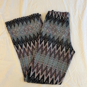Mönstrade boot cut byxor från KappAhl -  Snygga mönstrade byxor från KappAhl ”orrebyxorna”. Byxorna har ett coolt zigzag-mönster i svart, grönt och rosa. De är högmidjade och har en bekväm passform som sitter tight. Passar perfekt i många storlekar. Är själv S och 170cm