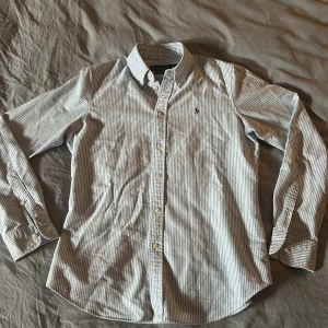 Ralph lauren skjorta randig - Säljer en klassisk blå- och vitrandig skjorta från Ralph Lauren i storlek M. Använd några gånger men utan fläckar och väldigt bra skick! Perfekt för både vardag och fest!