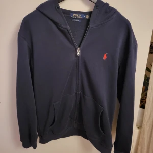 Mörkblå hoodie från Ralph Lauren - Säljer en snygg mörkblå hoodie från Ralph Lauren i storlek M, Men passar S.       klassiska röda logotypen på bröstet.
