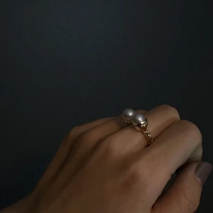 Guldfärgad ring med pärlor - Snygg guldfärgad ring med två stora vita pärlor. Perfekt för att ge en elegant touch till vilken outfit som helst. Ringen har en öppen design vilket gör den justerbar och bekväm att bära. Passar både till vardags och festliga tillfällen.