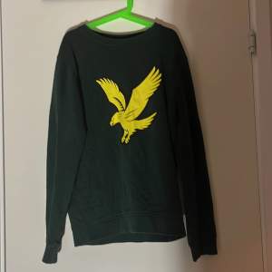 Säljer en snygg grön tröja från Lyle & Scott med ett coolt gult fågeltryck på framsidan. Tröjan är långärmad och perfekt för både skola och fritid. Den är i mycket bra skick och passar perfekt för höst och vår. Perfekt för den stilmedvetna unga! OBS!!! Pris kan diskuteras vid en snabb affär!