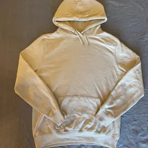 Säljer en stilren beige hoodie i mjukt bomullsmaterial. Perfekt för både höst och vår. Den har en klassisk passform med långa ärmar och en praktisk magficka. Huvan har dragsko för justering. Perfekt för en avslappnad look!