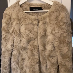 Beige pälsjacka från Vero Moda - Supermjuk och fluffig beige pälsjacka från Vero Moda. Perfekt för att hålla sig varm och stilren under kyliga dagar. Jackan har en enkel design utan krage och passar perfekt till vår och höstens kyliga dagar. Funkar utmärkt både till vardags och festliga tillfällen. Köparen får stå för frakten. 