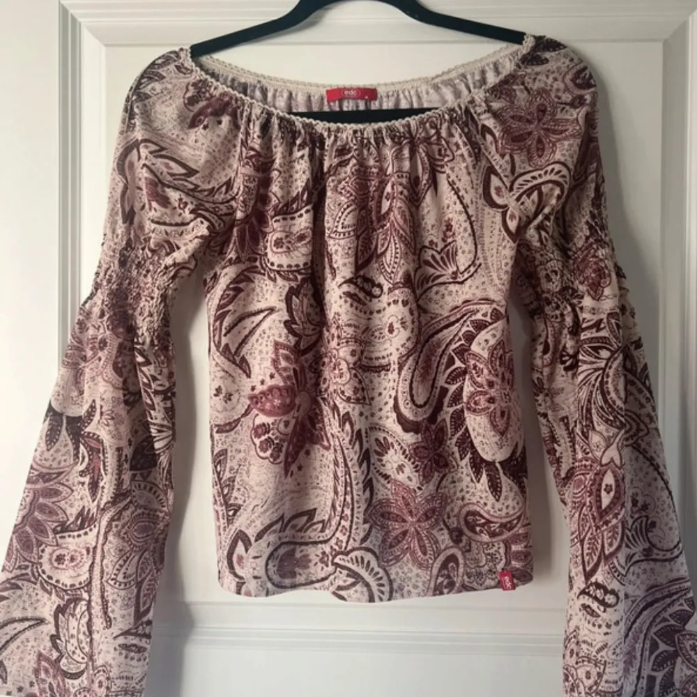 Säljer en superfin offshoulder topp från edc i storlek M. Den har ett snyggt paisleymönster i vinrött/rosa och beige. Toppen har vida långa ärmar med smockdetaljer. Perfekt för både vardag och fest!. Toppar.