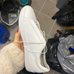 Vita sneakers från Vagabond - Säljer ett par stilrena vita sneakers från Vagabond i mycket bra skick. De är gjorda i skinn och har klassisk snörning. Perfekta för både vardag och fest! Passar till det mesta och är superbekväma. Storlek är inte angiven, men de ser ut att vara i normal passform.