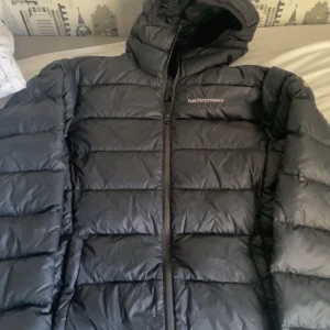 Svart dunjacka från Peak Performance - Säljer en svart dunjacka från Peak Performance i mycket bra skick. Jackan har en dragkedja framtill och en mysig huva. Perfekt för kalla vinterdagar och håller dig varm och bekväm. Passar både till vardags och utomhusaktiviteter.