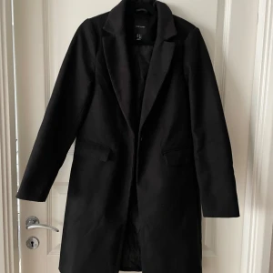 Svart kappa från New Look - Säljer en stilren svart kappa från New Look i storlek 34. Perfekt för höst och vinter med sin klassiska design och långa ärmar. Kappan har en elegant passform och är gjord i ett mjukt material som håller dig varm. Ett måste i garderoben för en chic look!