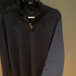 Mörkblå tröja i Merino & cotton blandning - Säljer en stilren mörkblå tröja i blandning av bomull och merinoull. Tröjan har en dragkedja vid halsen och är perfekt för både höst och vinter. Oanvänd! Köpt för 800kr i Lissabon! Pris går självklart att diskutera! ☺️