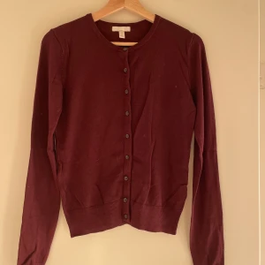 Vinröd kofta från H&M - Säljer en vinröd kofta från H&M i storlek XS. Den är i bra skick och har långa ärmar med knappar framtill. Perfekt för höst och vinter, och den är supermjuk och bekväm. Passar både till vardags och lite finare tillfällen. 🌟