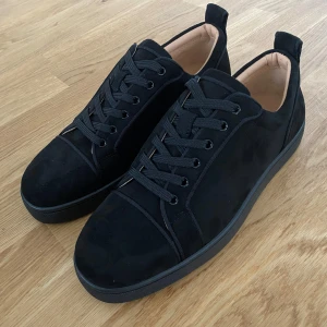 Svarta sneakers från Christian Louboutin - Säljer ett par snygga svarta sneakers från Christian Louboutin i mycket bra skick. Skorna är i mocka med klassisk röd sula och har snörning. Perfekta för både vardag och fest! Kommer med originalförpackning och dustbag. Helt oanvända.