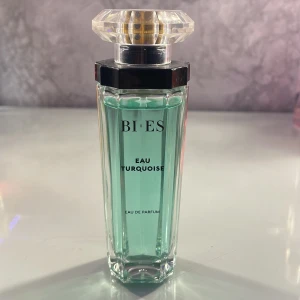 Eau Turquoise Eau de Parfum från BI-ES - Säljer en elegant Eau de Parfum från BI-ES med namnet Eau Turquoise. Flaskan är stilren och har en turkos färg som ger en fräsch känsla. Den har en unik, facetterad kork som ger en lyxig touch. Perfekt för dig som vill ha en fräsch och uppfriskande doft i din samling.