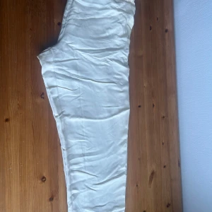 Beige byxor från H&M - Säljer ett par snygga beige byxor från H&M i storlek L. De är i nytt skick med etikett kvar. Byxorna har en bekväm passform med snörning i midjan och är perfekta för en avslappnad stil. Materialet känns mjukt och luftigt, vilket gör dem idealiska för vår och sommar.