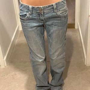 Lågmidjade jeans - Fina lågmidjade jeans med glitter detaljer. Midjemåttet rakt över är 38cm och innerbenslängden är 78cm. Byxorna är från aéropostale och är i bra skick!