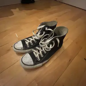 Säljer ett par klassiska svarta Converse All Star sneakers i bra skick. De har vita snören och en vit gummisula med lite slitage. Perfekta för vardagsbruk och ger en avslappnad stil. Storleken är inte angiven, men de passar de flesta. Lite ritade på men de e sånt som går o få bort! 