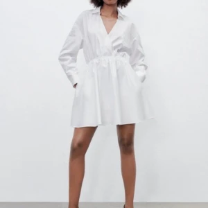 NY ZARA SKJORTKLÄNNING STORLEK XS - Vit klänning med långa ärmar och en v-ringning. Den har en elastisk detalj i midjan som ger den en figursydd siluett. Klänningen har fickor och underkjol. Aldrig använd med tags kvar. Säljs inte längre.