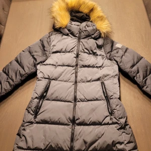 dunjacka från Reima - Säljer en supervarm dunjacka från Reima. Den har en fluffig fuskpäls på huvan och praktiska dragkedjor på fickorna. Perfekt för kalla vinterdagar! Jackan är i mycket bra skick och redo för nya äventyr. 🖤