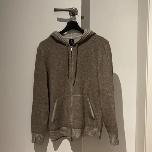 Beige hoodie från Boggi - Säljer en supermjuk beige hoodie från Boggi i kashmirblandning. Perfekt för kyliga dagar med dragkedja och ribbade muddar. Den har en klassisk design med fickor fram och en bekväm passform. Perfekt för både vardag och avslappnade tillfällen. Og pris 2700kr