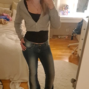 Grå croppad hoodie från Monki - Säljer en grå croppad hoodie från Monki i storlek S. Den har dragkedja och huva med snören, perfekt som en liten extra touch till sin outfit. Passar bra till både jeans och kjol. Använd  fåtal gånger så är i mycket bra skick. Perfekt för höst och vår!