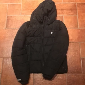 Svart pufferjacka från Superdry - Säljer en svart pufferjacka från Superdry i mycket bra skick. Knappt använd, bara någon enstaka gång. Nypris ligger på ca 1400 kr men säljer denna för endast 999 kr. Priset är dock inte hugget i sten än så vill du förhandla är det bara att skicka ett meddelande 🙌🏻 Snabb service och frakt