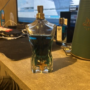 Jean Paul Gaultier Le Beau Parfym - Säljer en flaska Jean Paul Gaultier Le Beau parfym. Flaskan har en unik design i form av en manlig torso i blått glas med en guldig detalj framtill. Parfymen kommer i en elegant grön metallförpackning med guldtext. Perfekt för den som vill ha en stilren och maskulin doft. Pris går att diskuteras😁