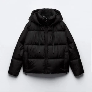 Svart pufferjacka från Zara - Säljer en svart pufferjacka från Zara i mycket bra skick. Jackan har en dragkedja framtill och en mysig huva. Perfekt för kalla höst- och vinterdagar. Den är både stilren och praktisk med sin quiltade design. Den har en liten skada på ena armen, som kan lagas väldigt enkelt. 