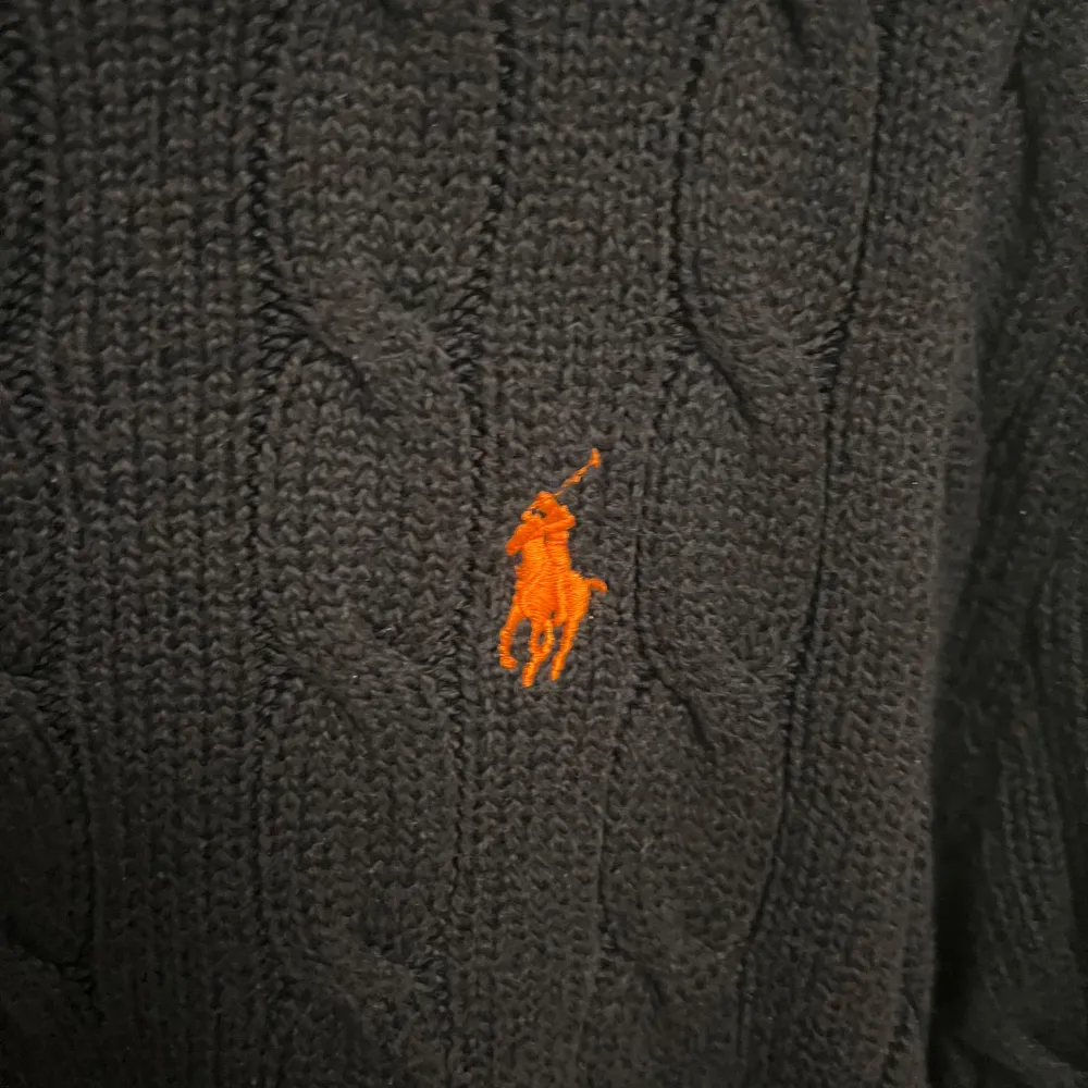 Säljer en snygg mörkblå stickad tröja från Polo Ralph Lauren. Den har ett klassiskt flätmönster och den ikoniska loggan broderad i orange på bröstet. Perfekt för höst och vinter, med långa ärmar och en bekväm passform. Passar både till vardags och lite finare tillfällen. Ny pris på denna ligger på ca 2500kr, mitt pris 1000kr!! Hör av er för fler bilder eller funderingar 😁. Tröjor & Koftor.