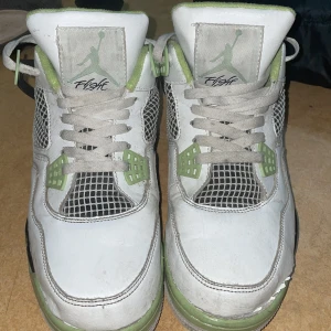 Nike Air Jordans i vitt och grönt - Säljer ett par Nike Air Jordans i vitt och grönt. Skorna har snörning och en cool design med gröna detaljer och svart logga på hälen. De är i bra skick med lite slitage på sulan. Perfekta för både vardag och fest!