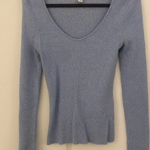 Ljusblå ribbad tröja från H&M - Säljer en superfin ljusblå ribbad tröja från H&M. Den har en v-ringad design och långa ärmar, perfekt för både vår och höst. Tröjan är i bra skick och passar perfekt för en casual look. Skön och stilren, ett måste i garderoben! 💙