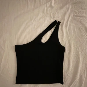 Svart oneshoulder topp från NA-KD - Snygg svart oneshoulder topp från NA-KD i storlek XS. Perfekt för en utekväll eller fest!