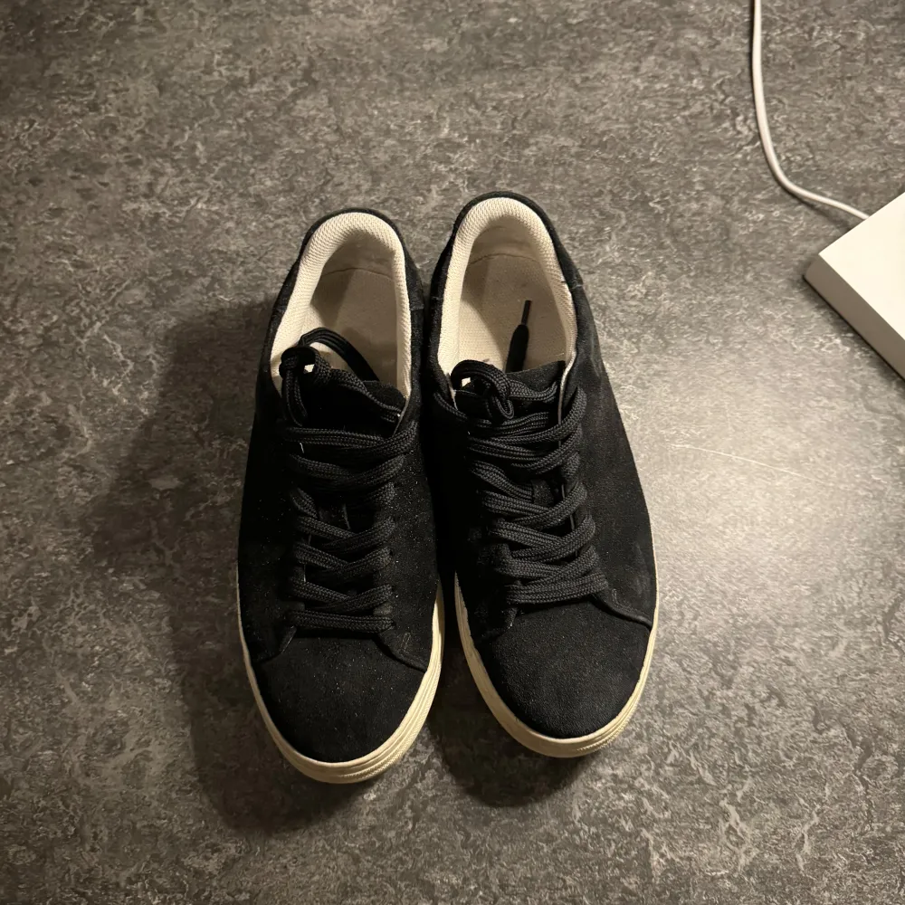 Säljer ett par stilrena svarta sneakers från Selected Homme i storlek 41. Skorna är i mocka med en vit sula och har klassisk snörning. Perfekta för både vardag och fest! 🖤. Skor.