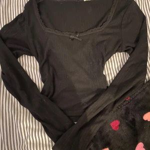 Svart ribbad topp från H&M Divided - Säljer en svart ribbad topp från H&M Divided i storlek S. Toppen har långa ärmar och en söt spetsdetalj runt halsringningen. Jag säljer för att den inte kommer till användning.❣️