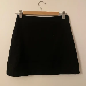Svart kjol - Snygg svart kortkjol. Den har en enkel design utan mönster eller detaljer, vilket gör den lätt att matcha med olika toppar och accessoarer. Ett måste i garderoben för alla säsonger!🖤 