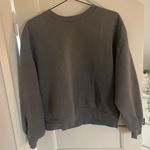 Grå sweatshirt från Gina Tricot - Säljer en grå sweatshirt från Gina Tricot i helt okej skick. Den har en normal passform med långa ärmar och ribbade muddar vid ärmslut och nederkant. Perfekt för en avslappnad stil under höst och vår.