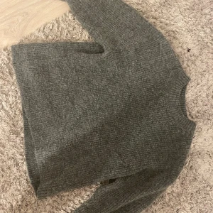 Grå stickad tröja - Mysig grå stickad tröja i damstorlek XS. Perfekt för kyliga dagar med sin varma och bekväma design. Tröjan har långa ärmar och en klassisk rund halsringning. Passar perfekt till både vardag och mysiga hemmakvällar.