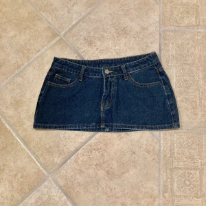 Lågmidjad Jeanskjol  - Minikjol i mörk denim med låg midja. Kjolen är i stl XS och är i mycket gott skick då den aldrig är använd. Klicka gärna på köp nu och meddela för eventuella frågor. :)