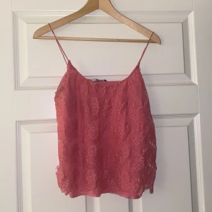 Rosa spetslinne från Gina Tricot - Säljer ett supersött rosa spetslinne från Gina Tricot i storlek S. Perfekt för sommardagar eller en festlig kväll. Linnet har tunna axelband och ett vackert spetsmönster som ger en romantisk touch. Passar både till jeans och kjol!