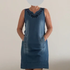 Jeansklänning från Tom Tailor - Säljer en superfin jeansklänning från Tom Tailor i storlek 32. Klänningen är ärmlös och har en snygg broderad detalj vid halsringningen. Den är i en klassisk blå jeansfärg och har en normal passform. Perfekt för vår och sommar!