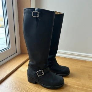Svarta stövlar med dragkedja och spännen - Säljer ett par svarta stövlar med dragkedja baktill från The Urban Project. Perfekta för höst- och vinterväder! Stövlarna är i bra skick, använda endast enskilda tillfällen (mest legat i garderoben). Nypris 2000kr💕